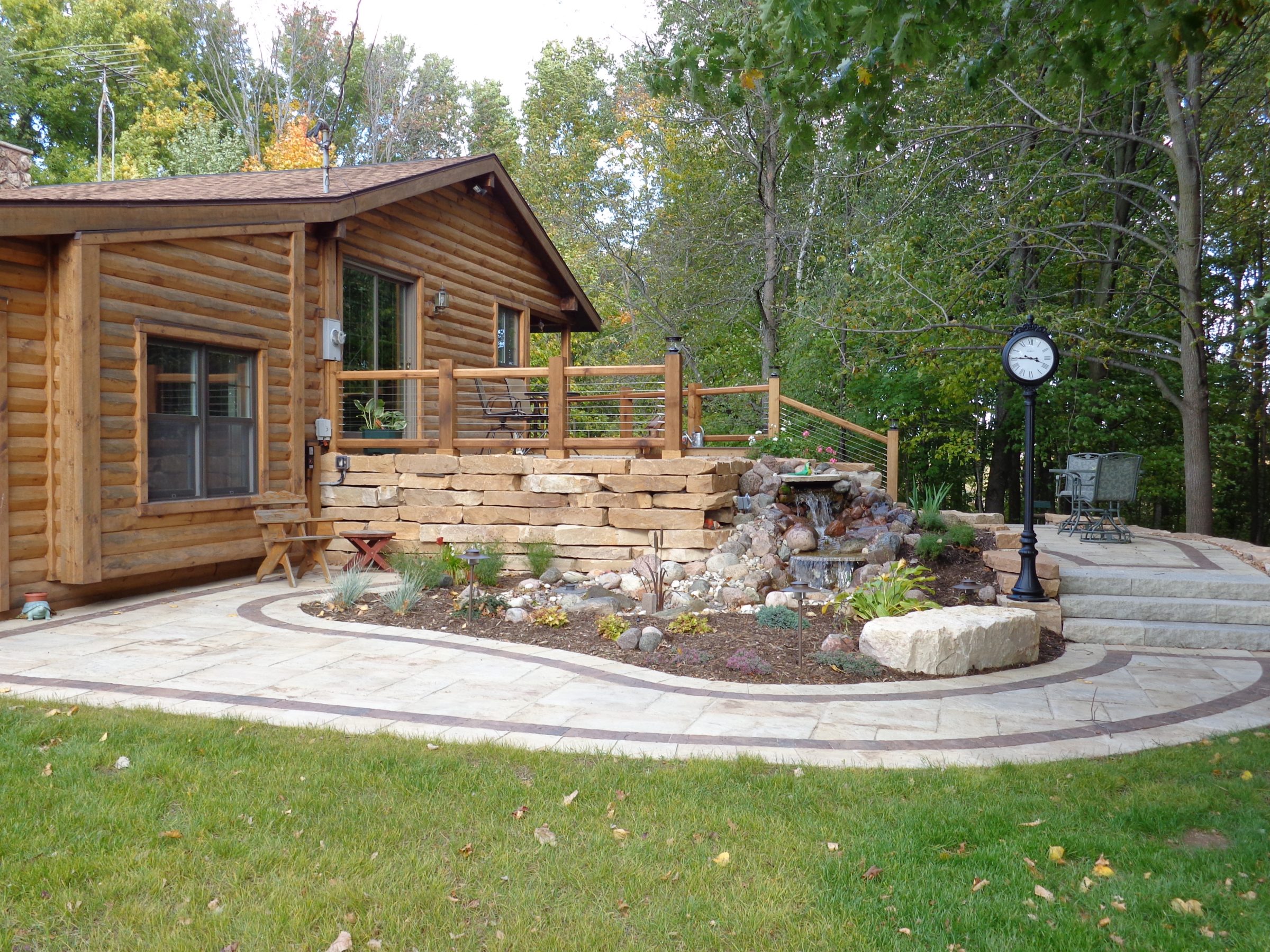 Log cabin with deck and stone waterfall patio