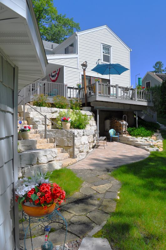 White house with deck and stone steps garden