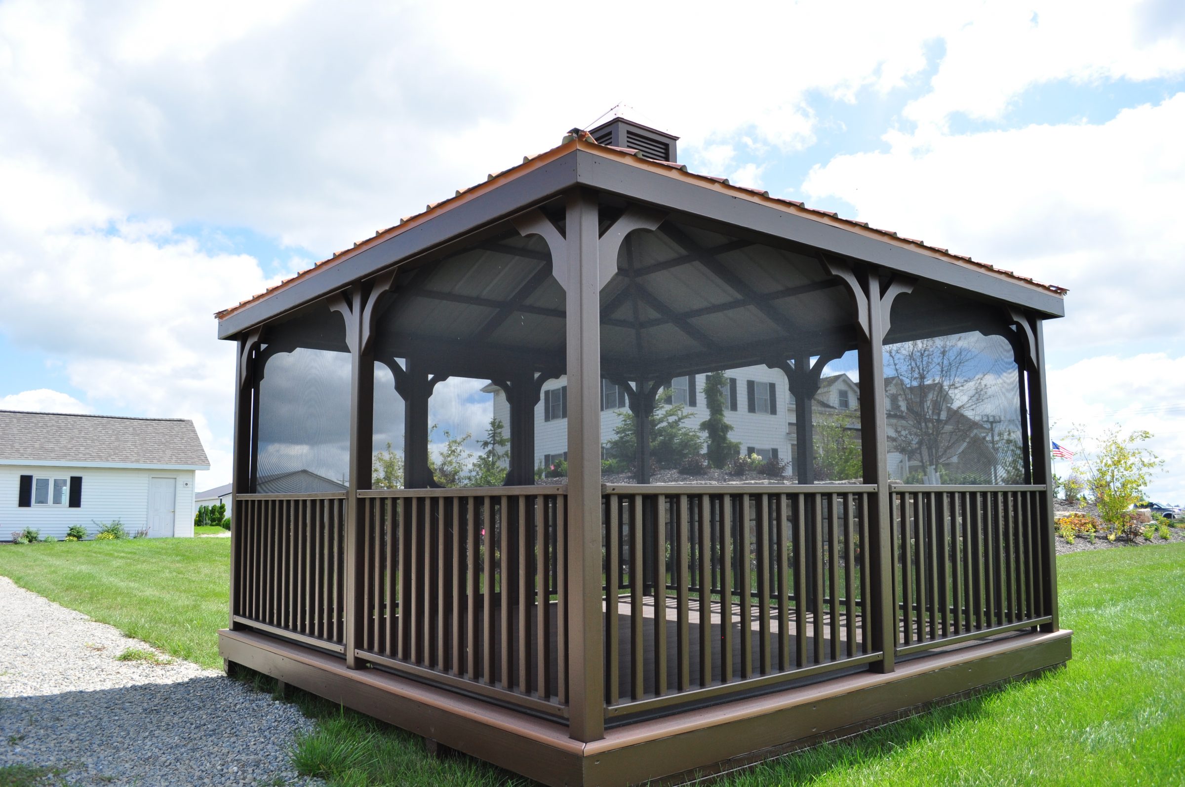 Screened wooden gazebo in suburban backyard lawn