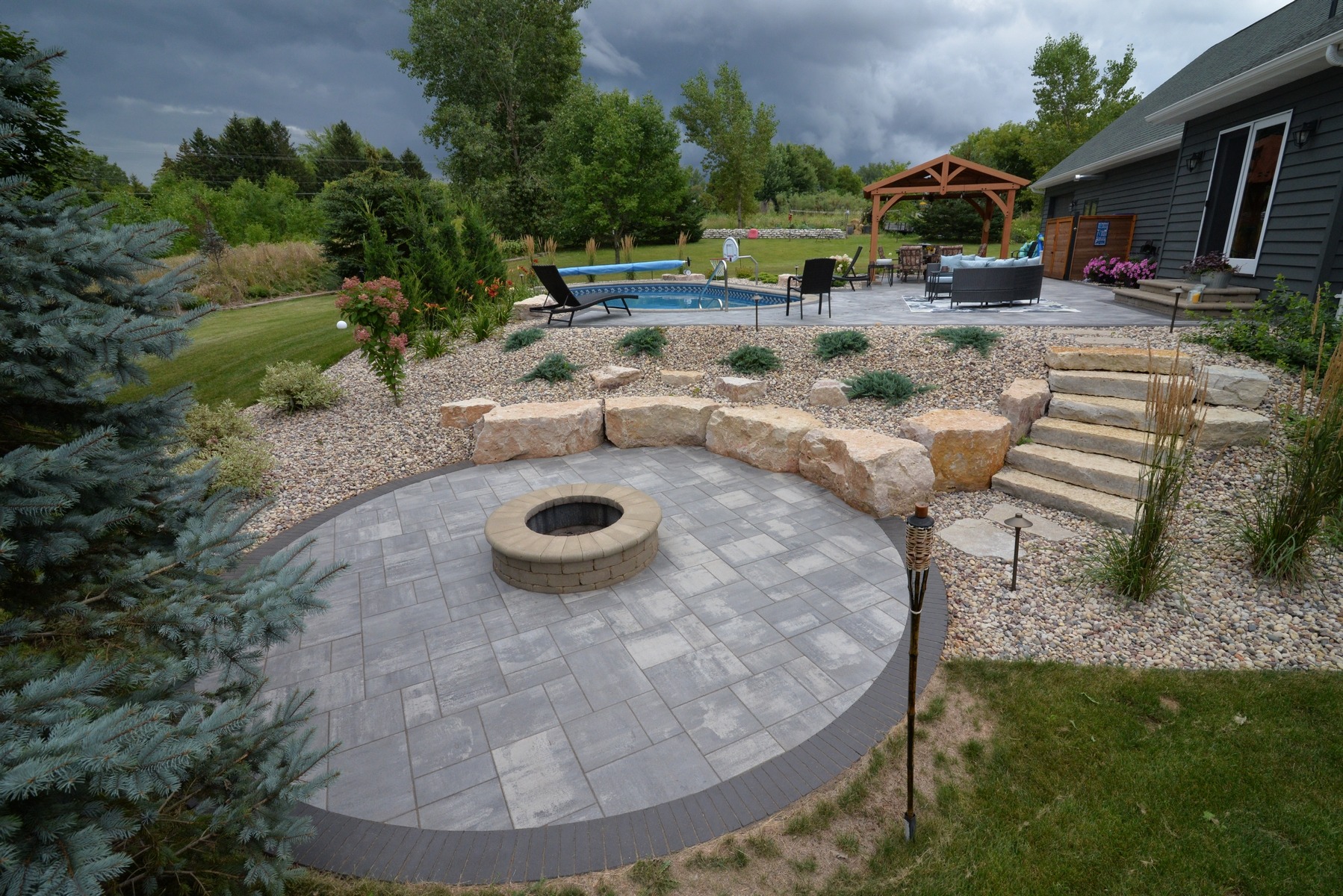 Landscaped backyard with fire pit, pool, and patio