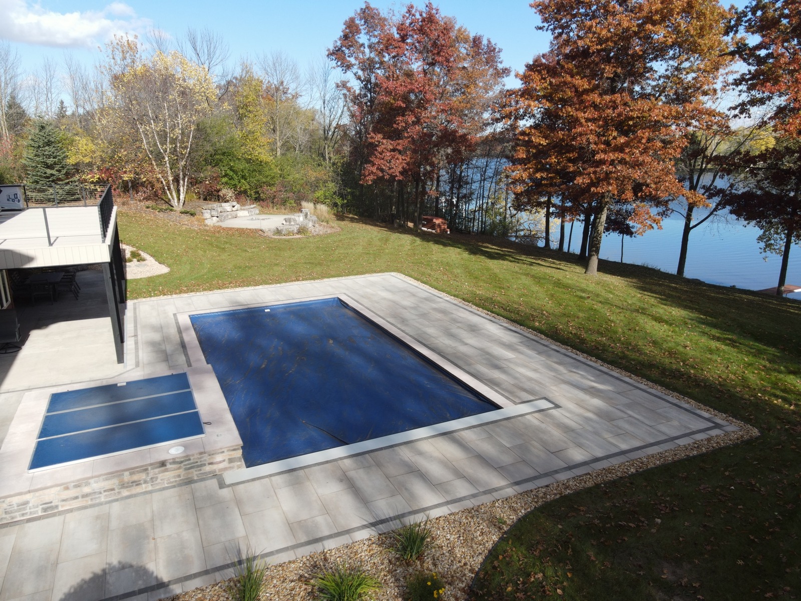 Covered backyard pool beside autumn lakeside home