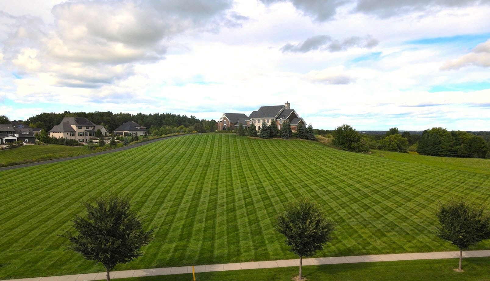 Large striped lawn with houses on hill