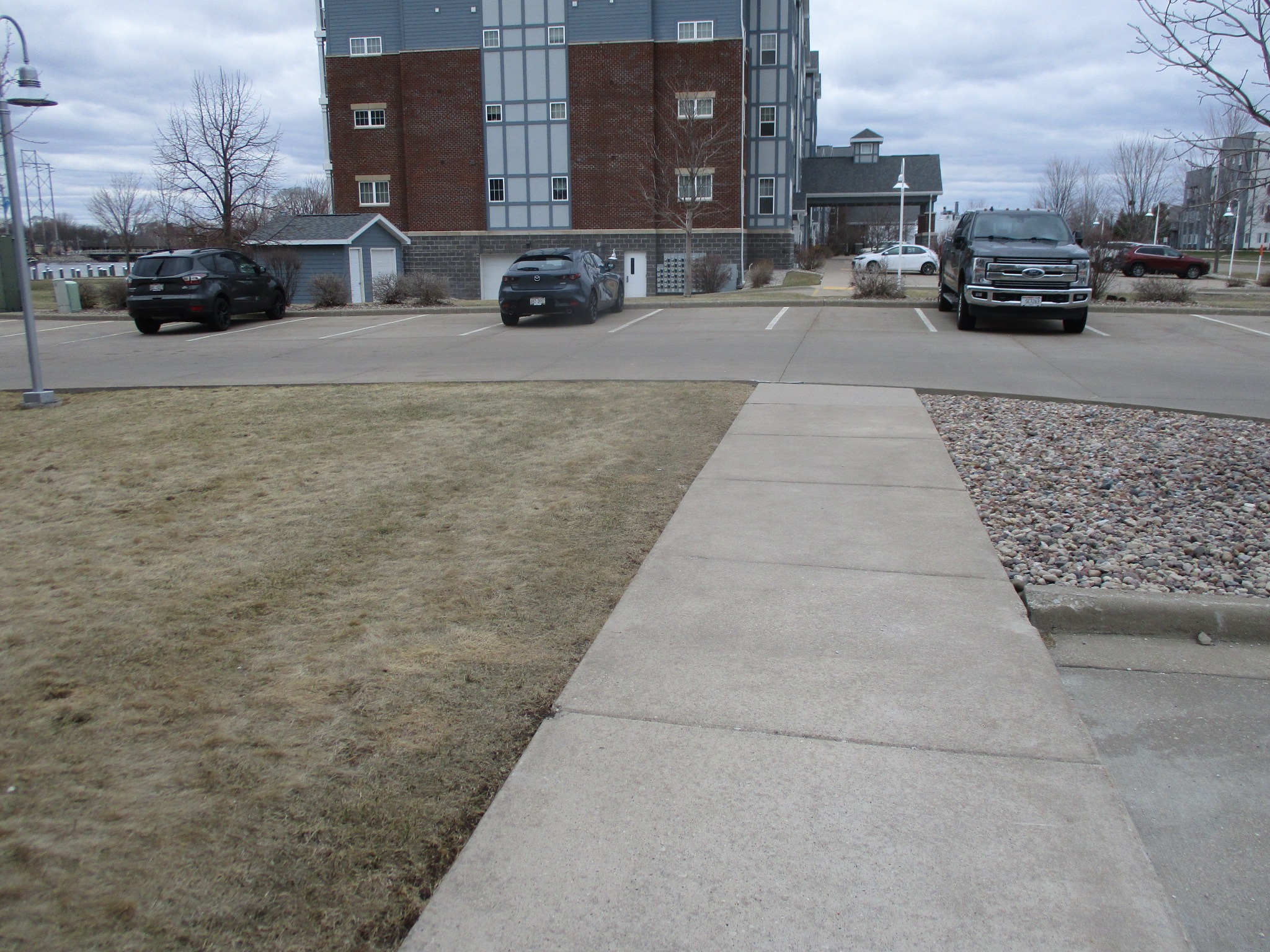 Apartment parking lot with sidewalk and parked cars