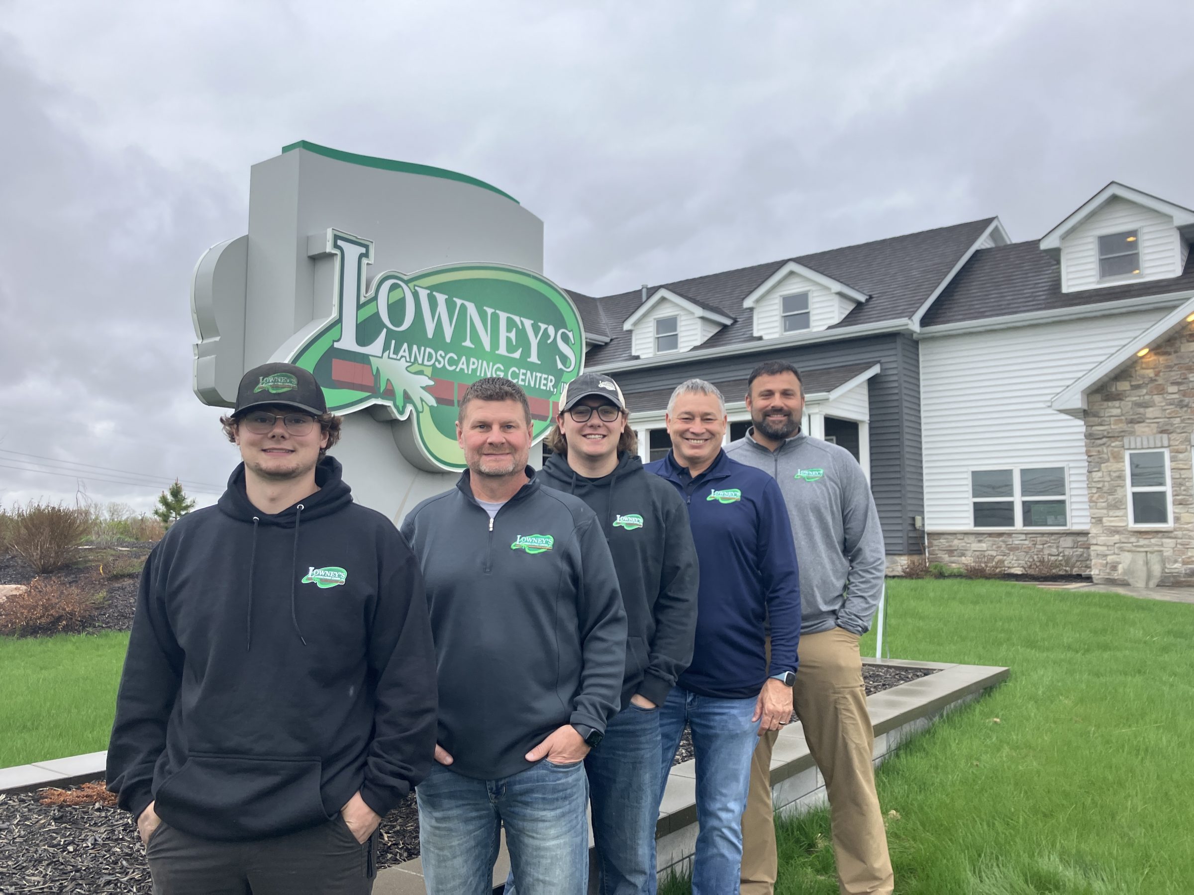Team standing outside Lowney's Landscaping Center sign