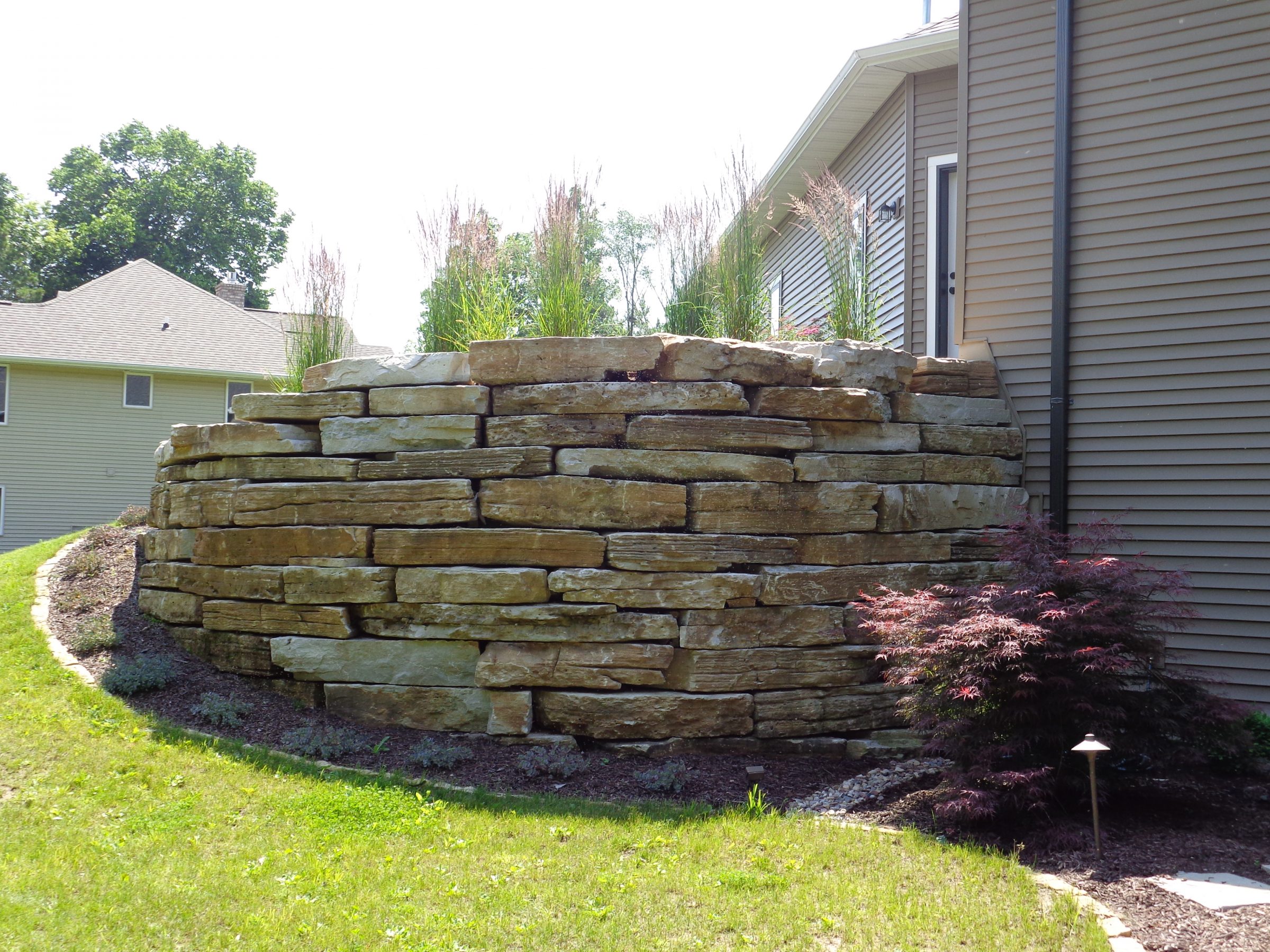 Stacked stone retaining wall beside suburban home