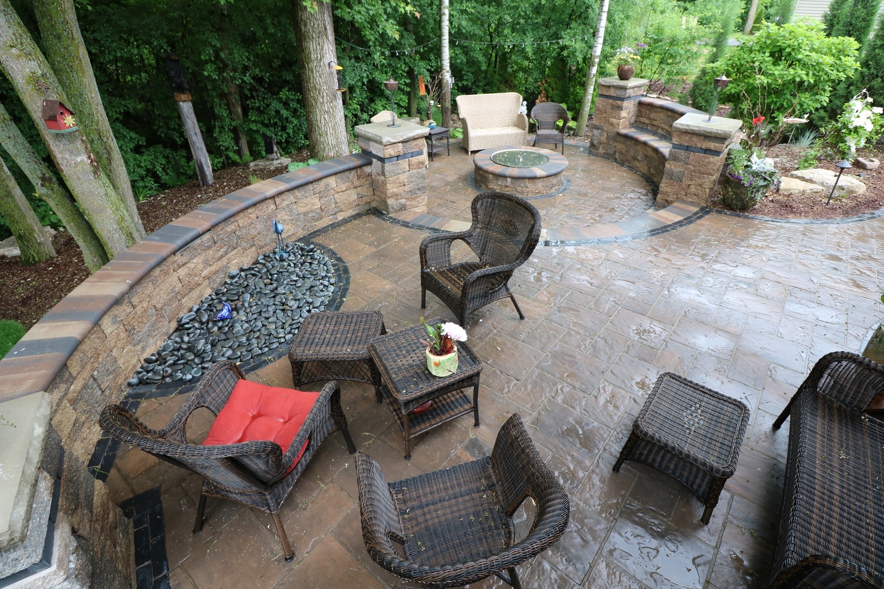 Landscaped backyard patio with wicker seating and fire pit