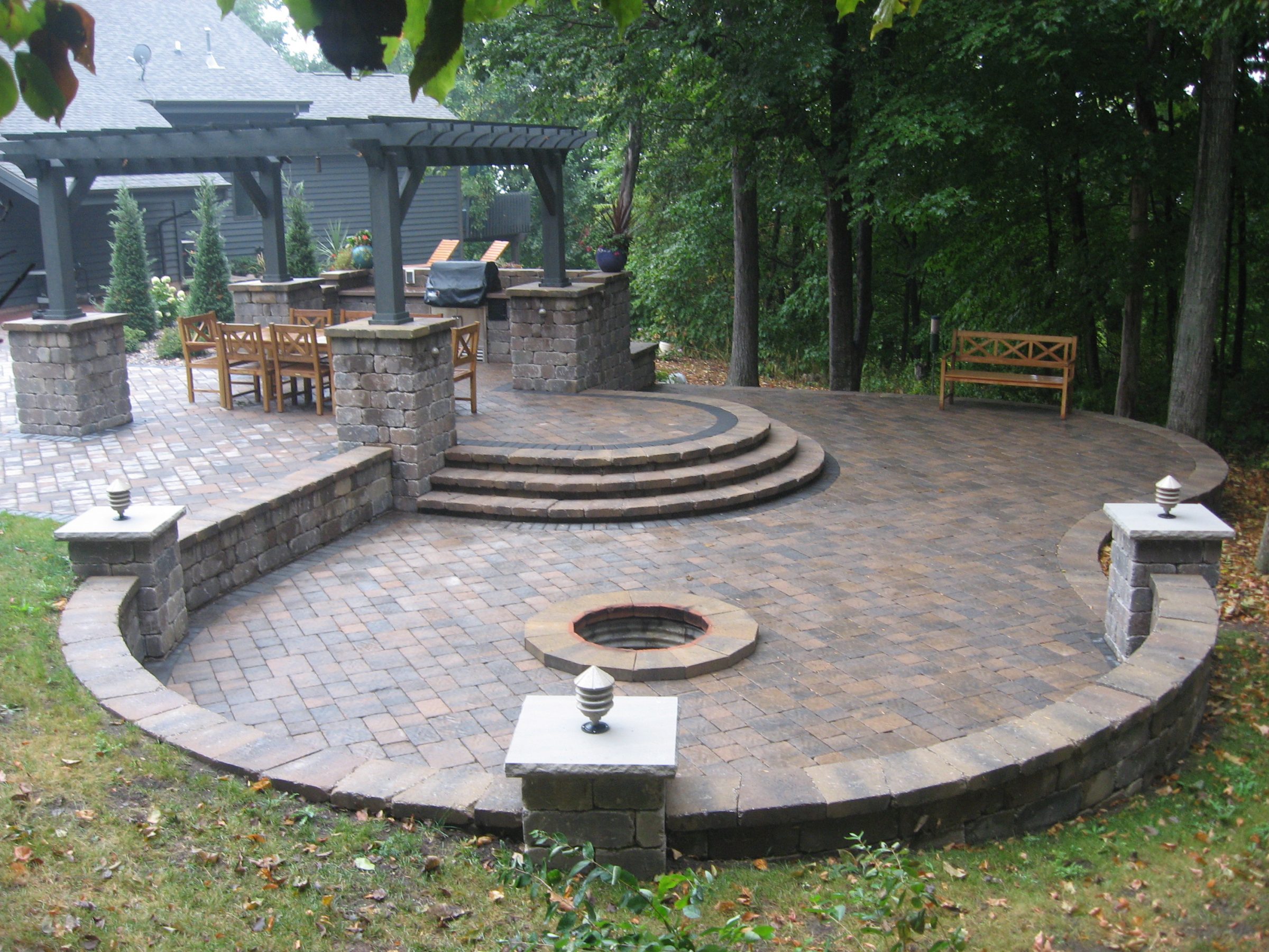 Stone patio with pergola and circular fire pit