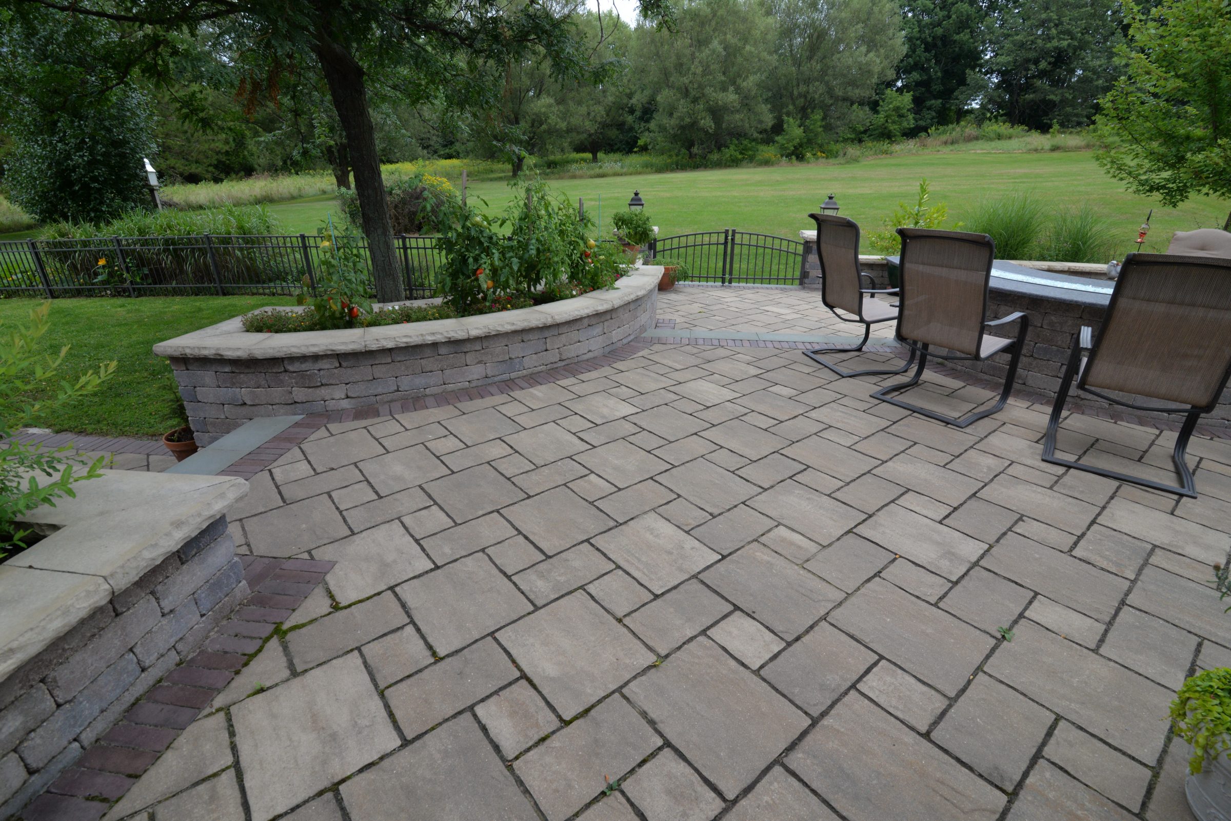 Stone patio with chairs overlooking green backyard