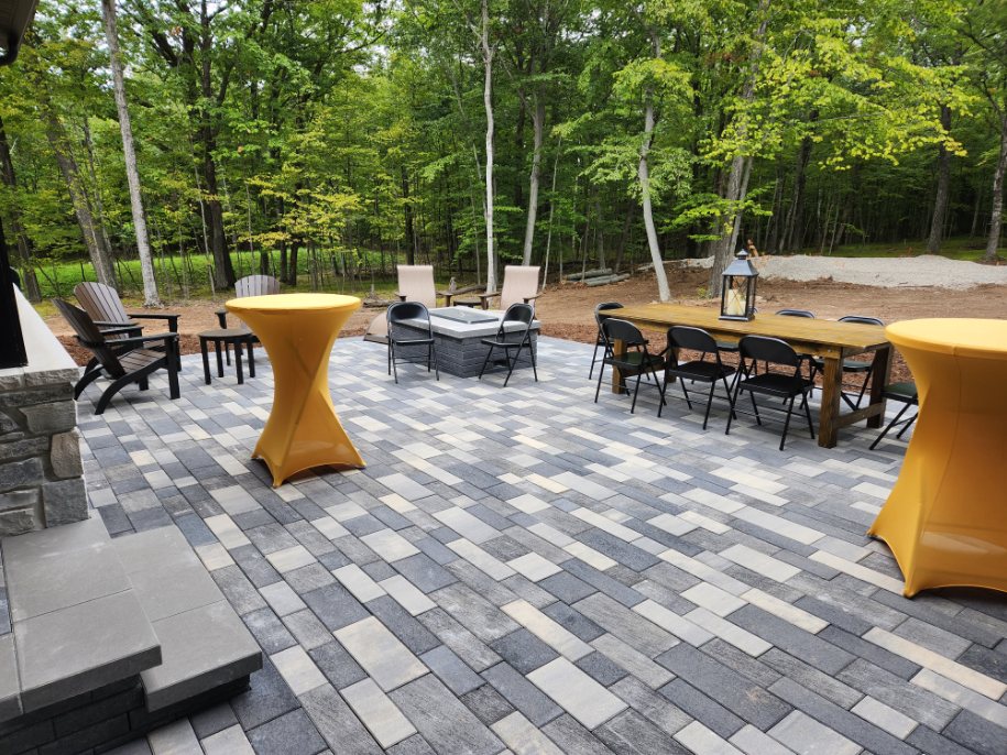 Outdoor patio with pavers, tables, and forest backdrop