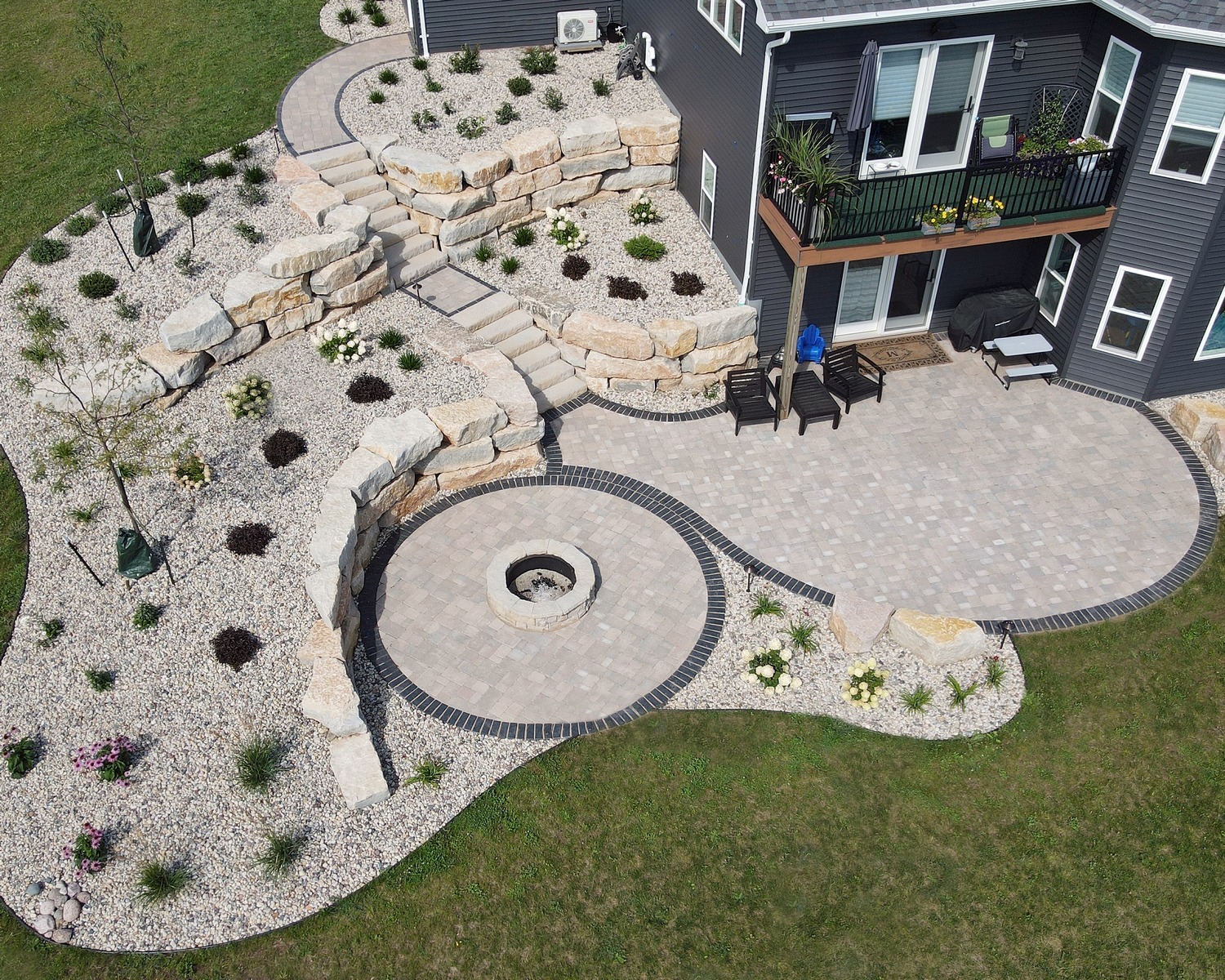 Landscaped backyard patio with fire pit and stone walls