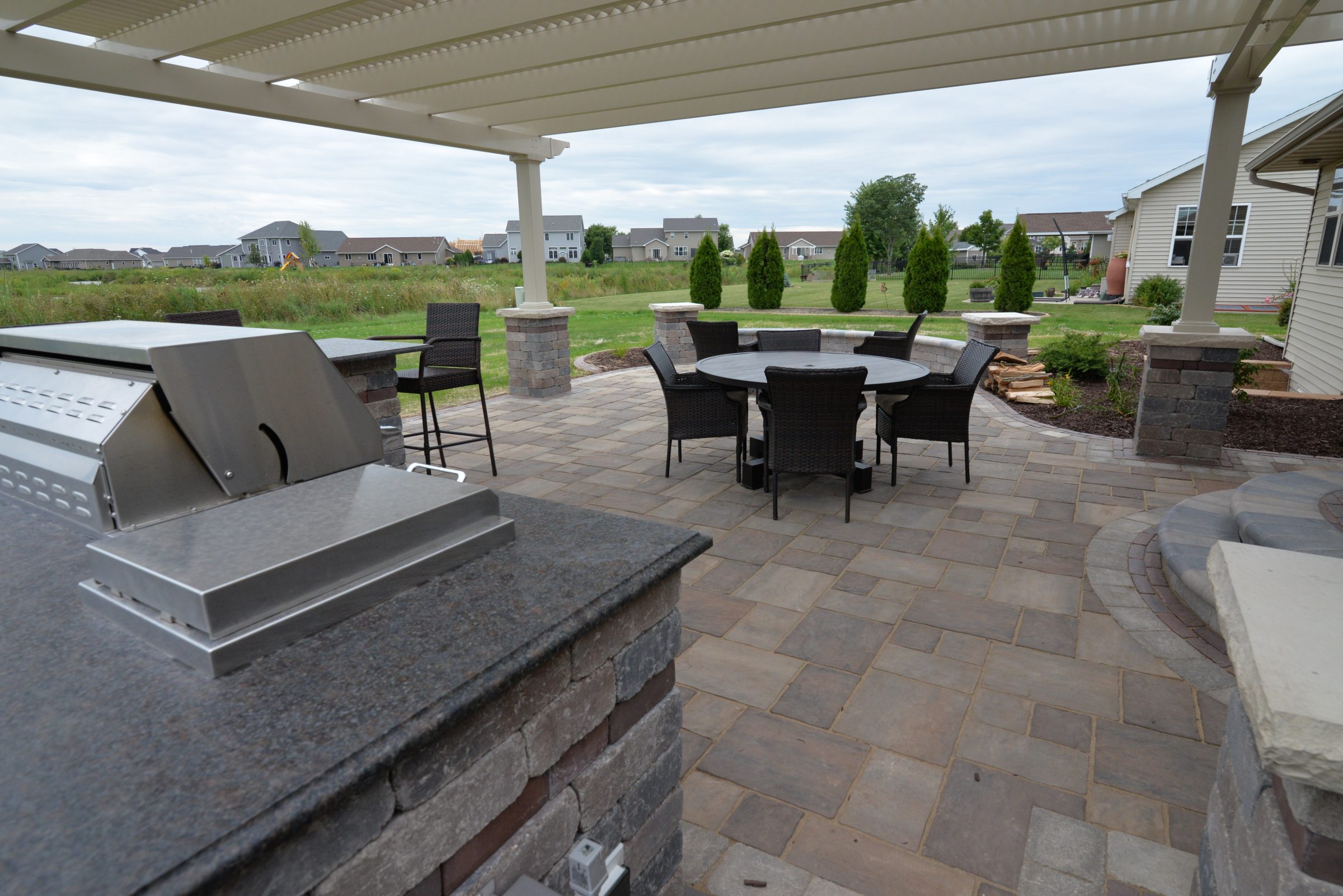 Backyard patio with pergola, grill, and dining set