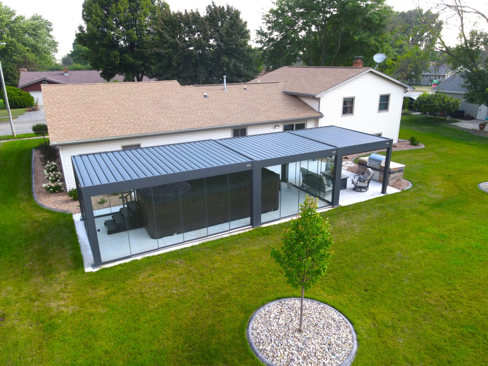 Modern glass patio enclosure behind suburban home