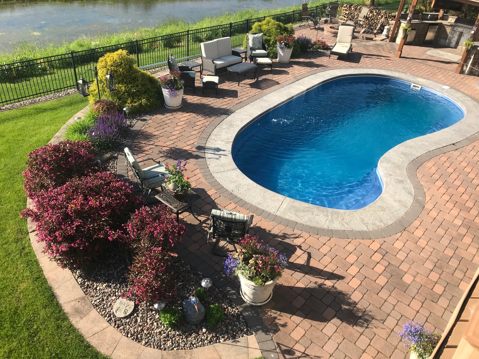 Landscaped backyard pool with brick patio and river view