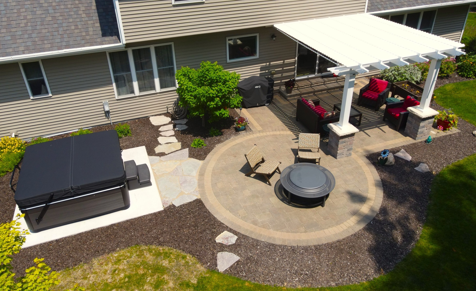 Backyard patio with pergola, fire pit, and hot tub