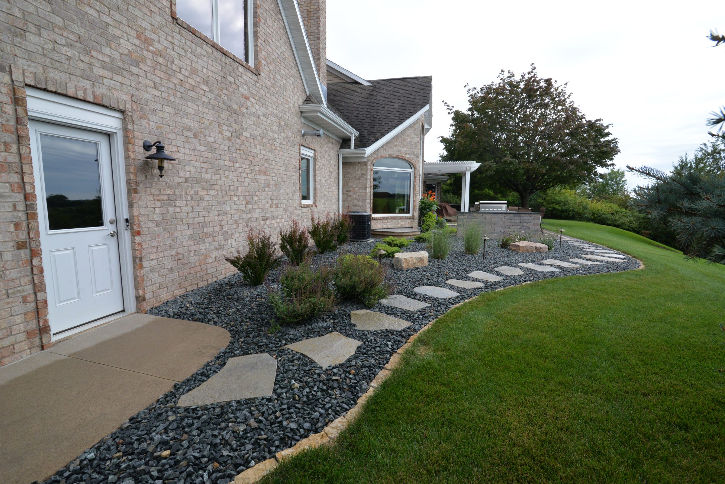 Brick house with landscaped backyard and stone pathway