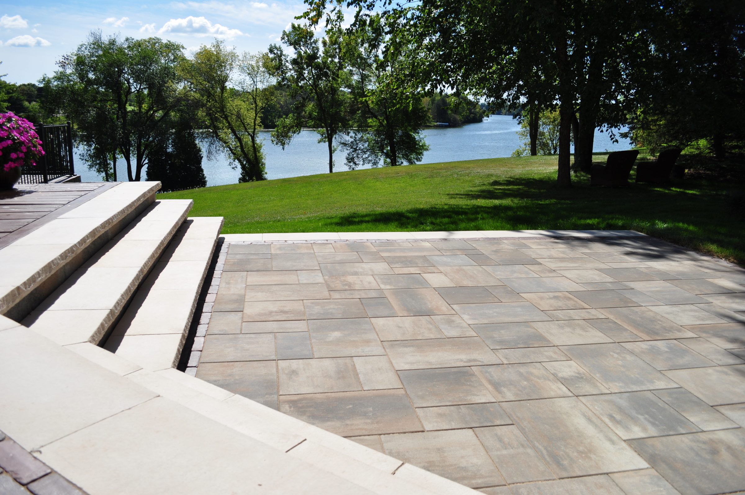 Stone patio overlooking green lawn and lakeside trees