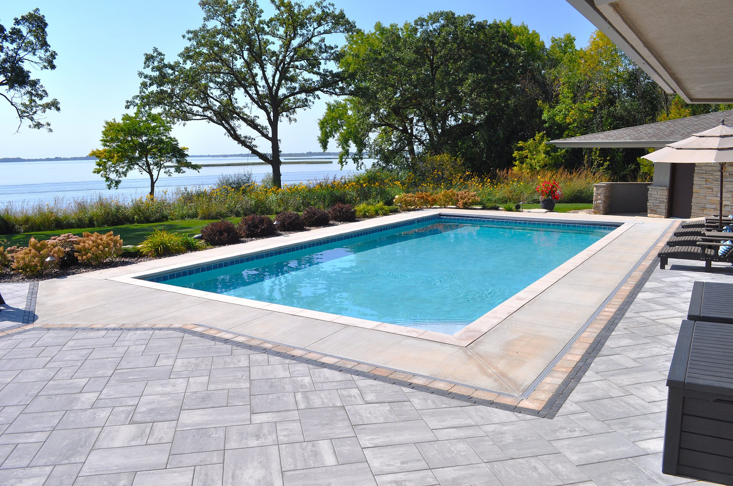 Modern backyard pool overlooking serene lakeside landscape
