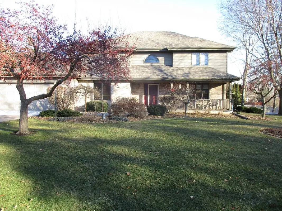 Two-story suburban house with front lawn and trees