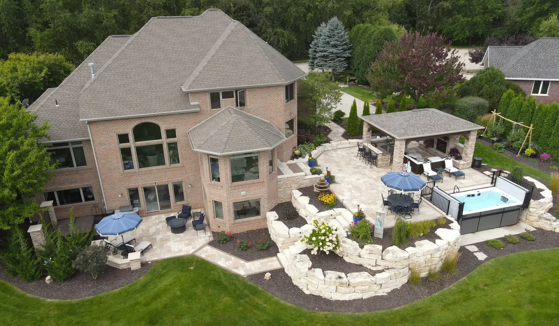 Large brick home with landscaped patio and hot tub