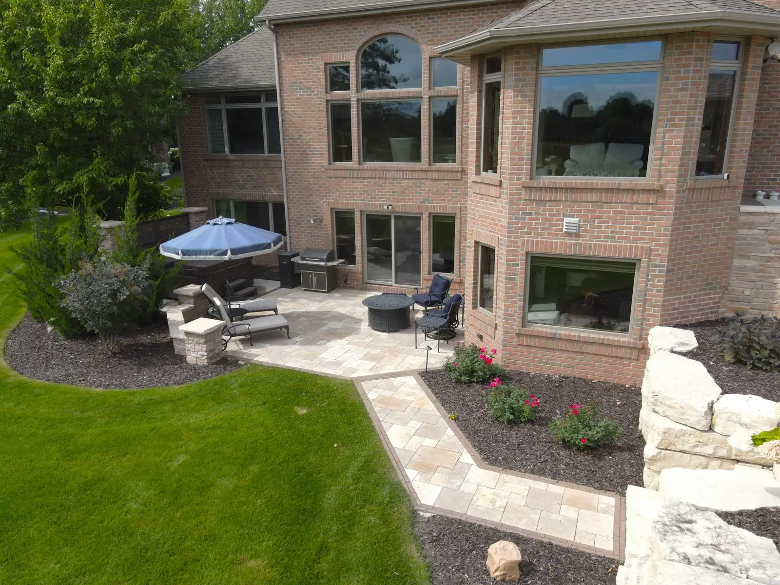 Brick house backyard patio with seating and umbrella