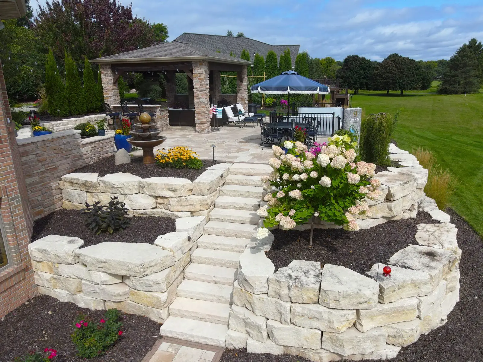 Landscaped backyard patio with stone walls and gazebo