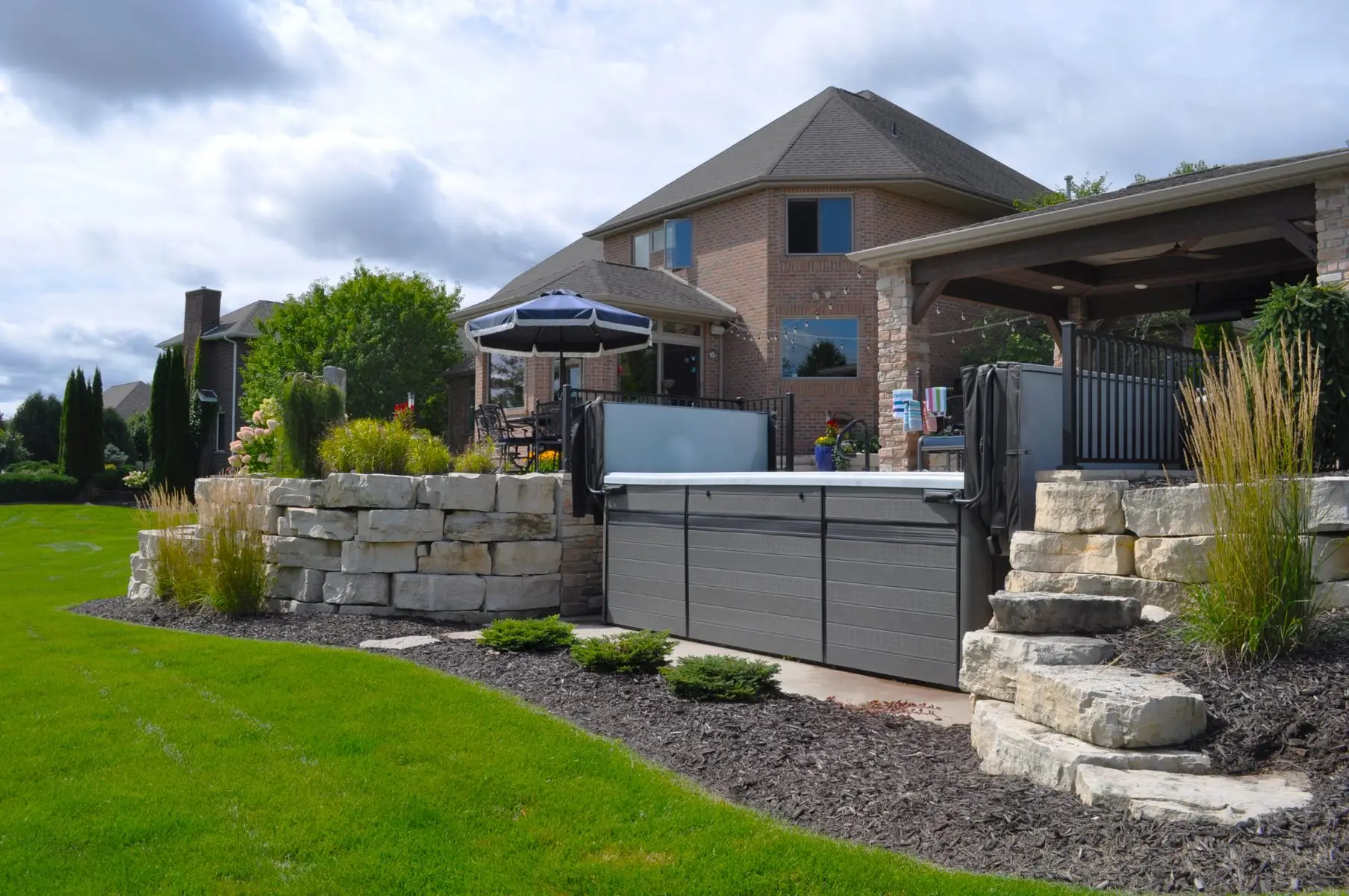 Backyard patio with hot tub and stone landscaping