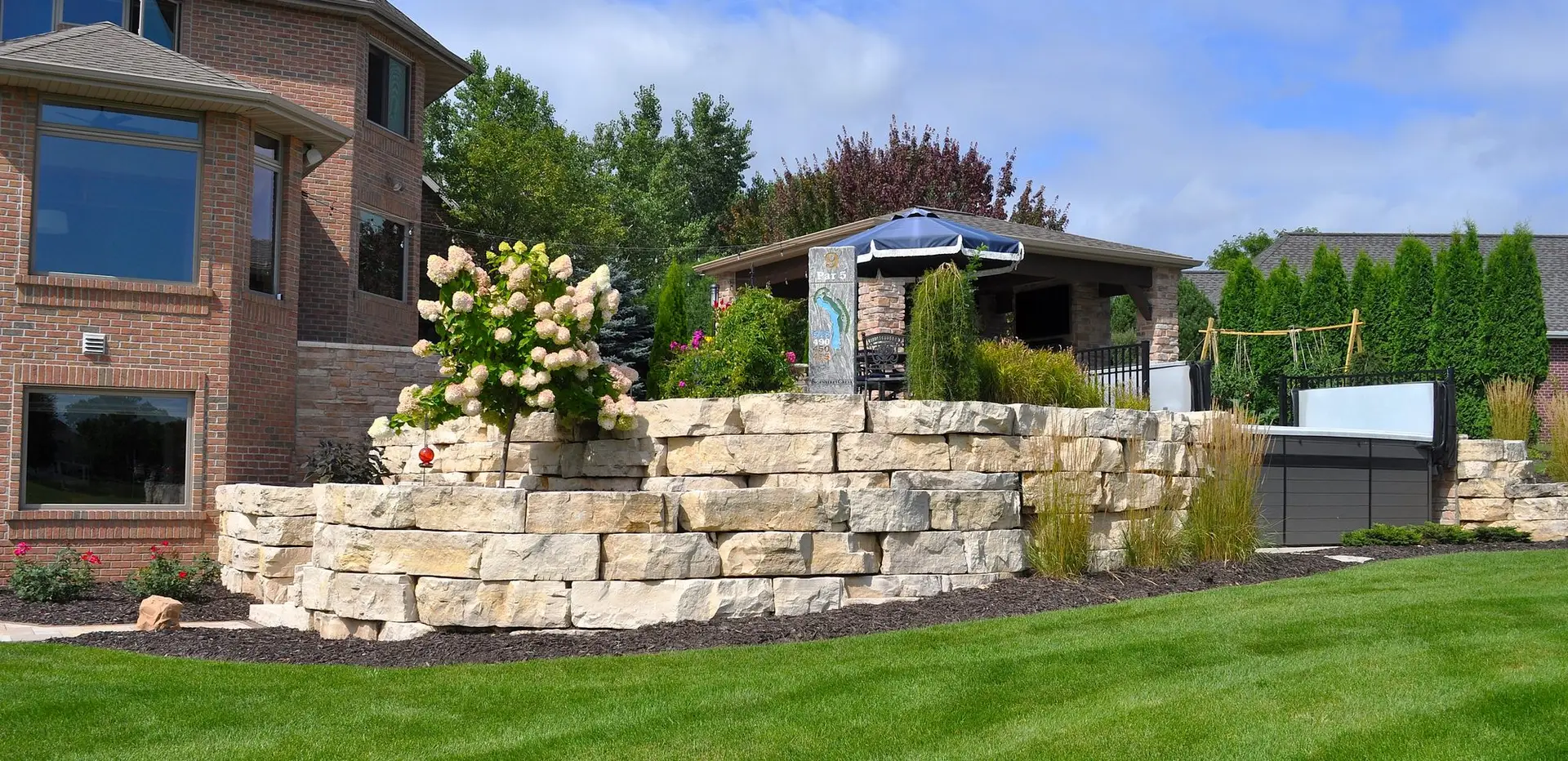 Landscaped backyard with stone retaining wall and gazebo