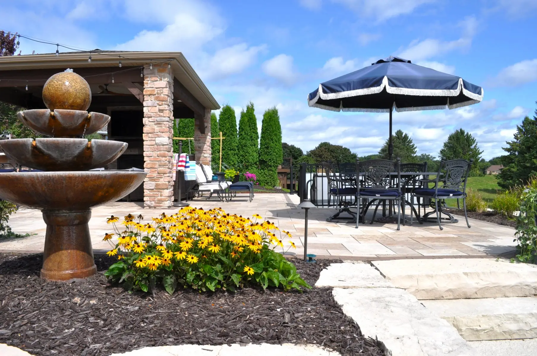 Landscaped patio with fountain and umbrella table