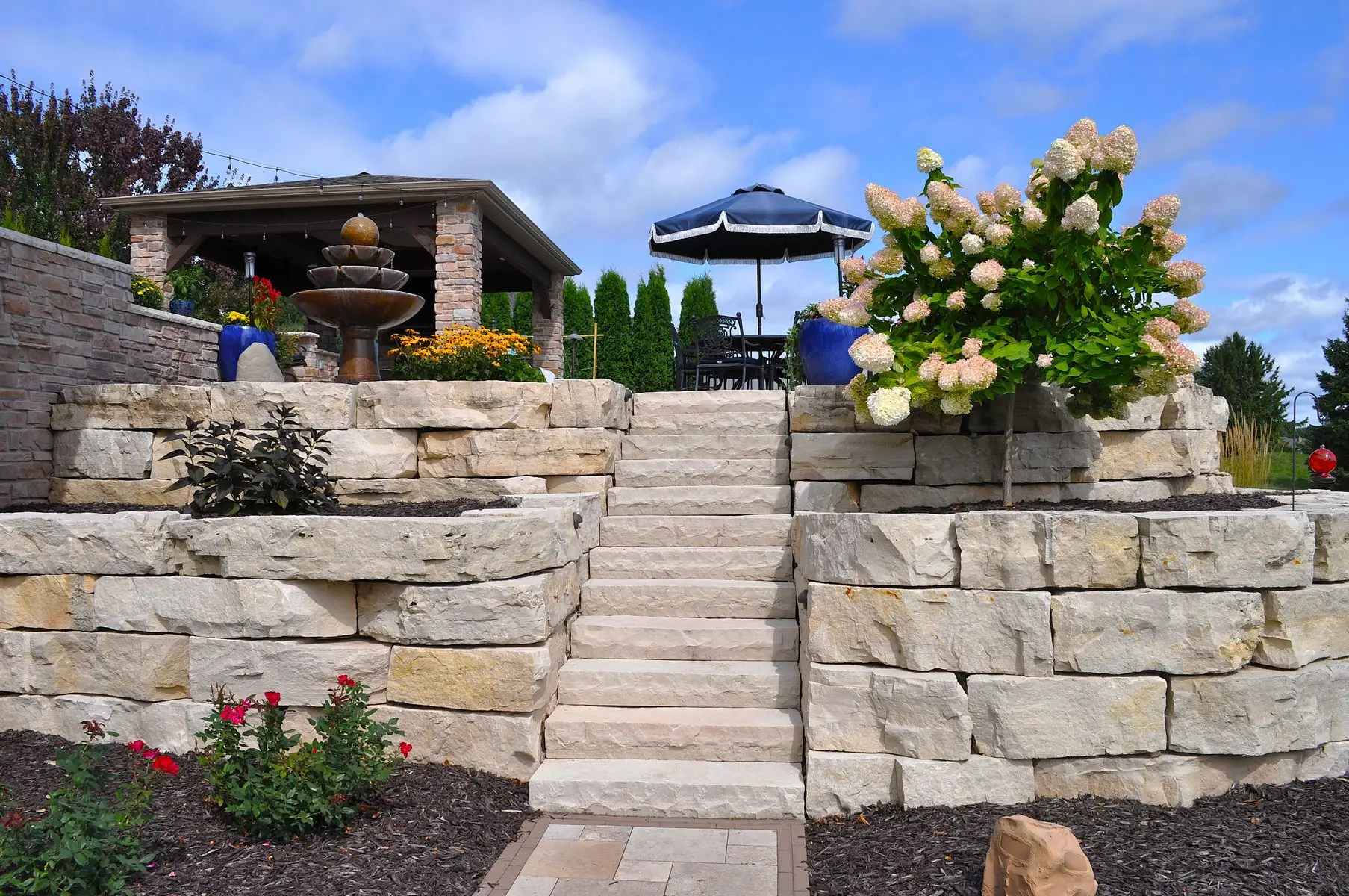 Stone patio with steps, fountain, and garden