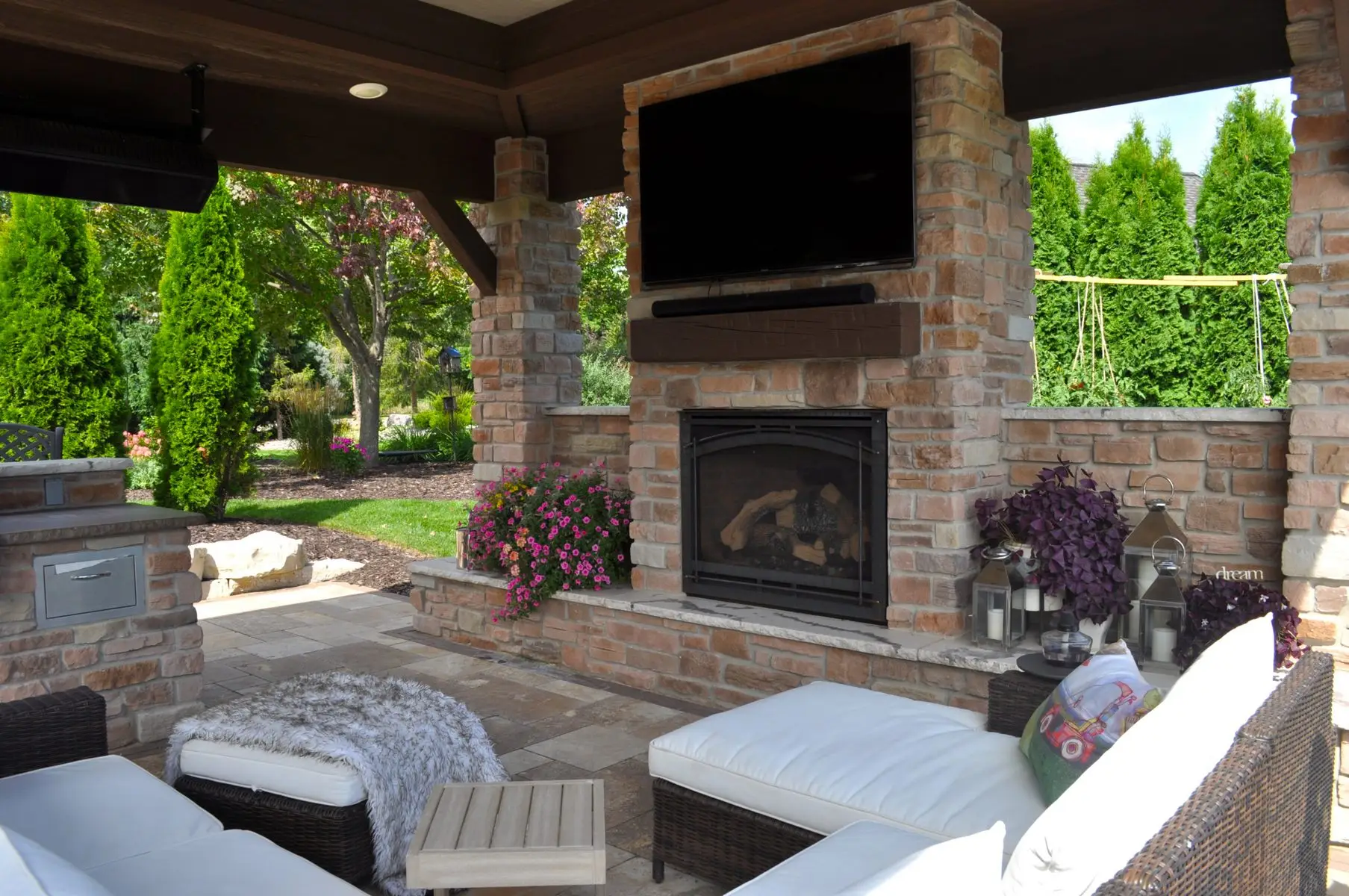Outdoor patio with stone fireplace and TV