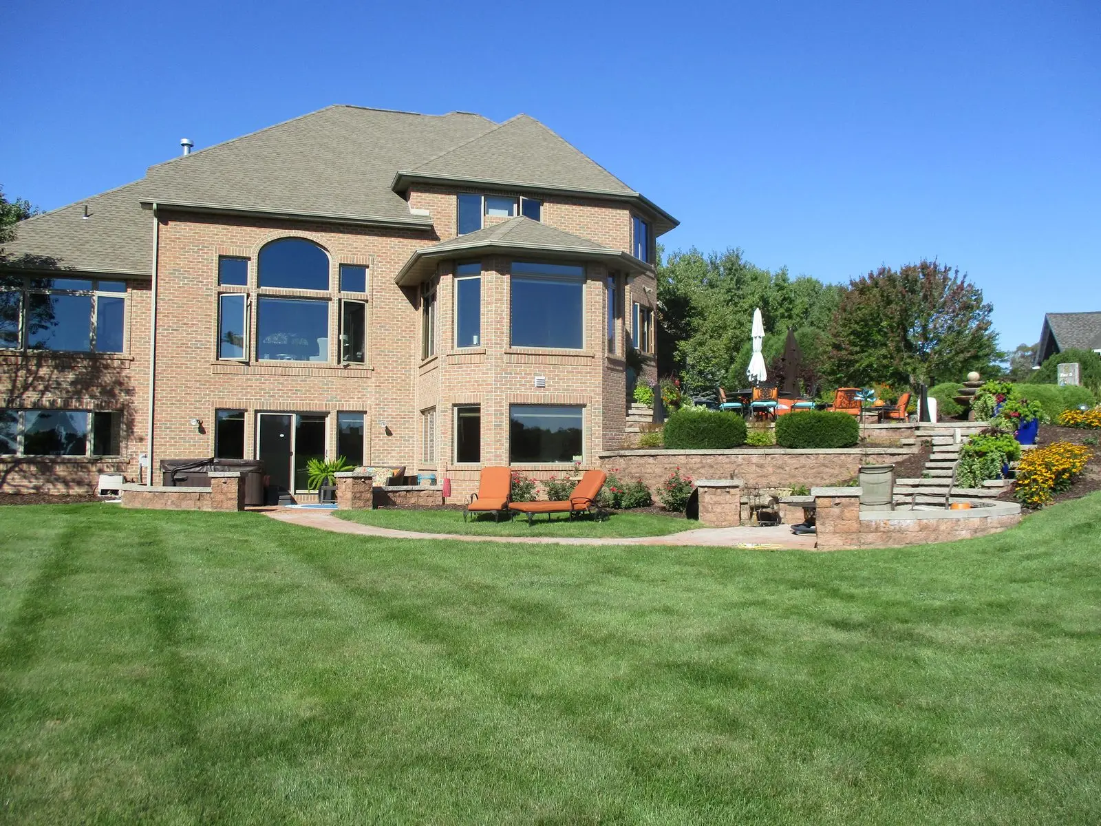 Large brick house with landscaped backyard and patio