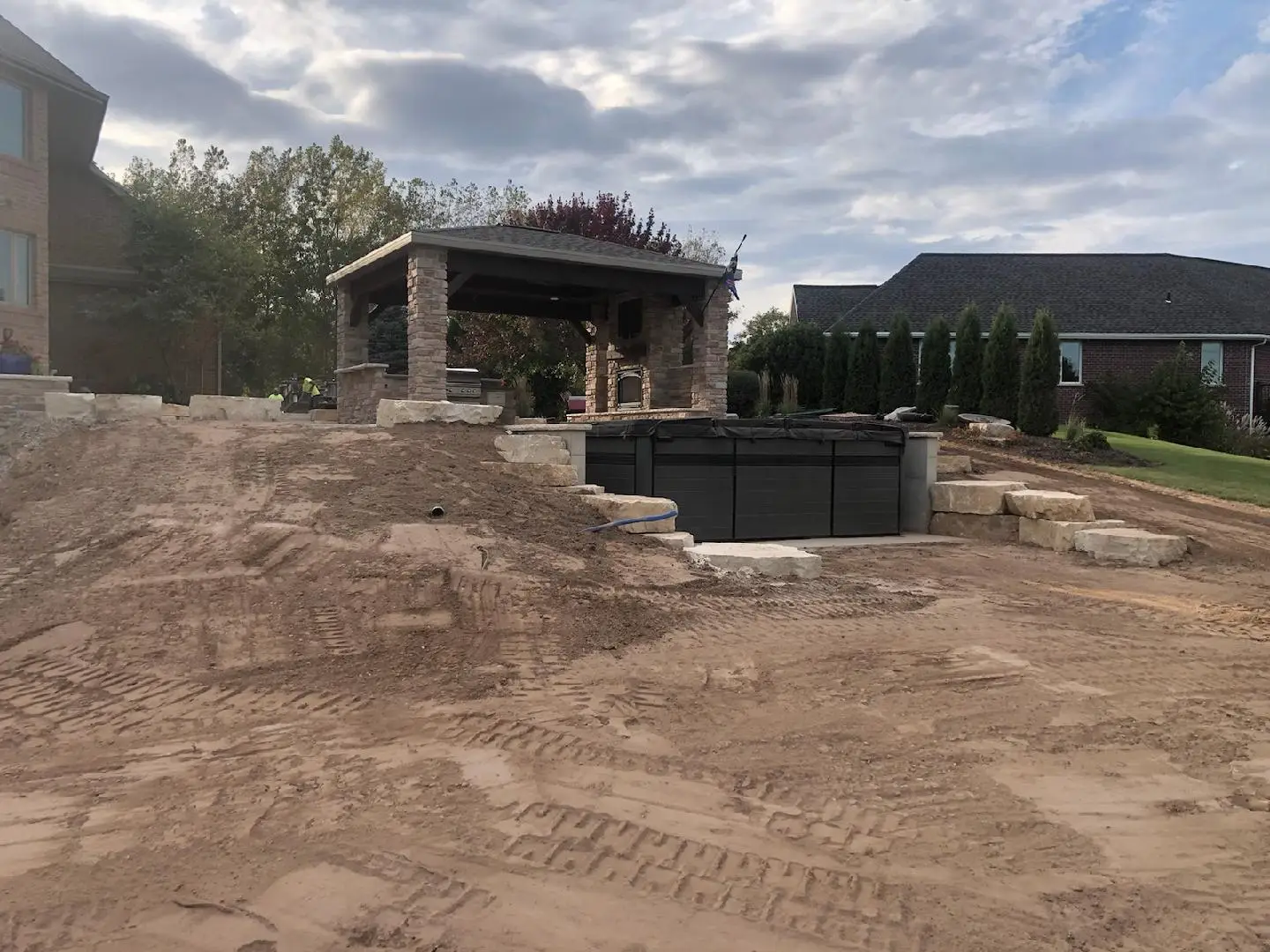Backyard construction with stone pavilion and pool installation