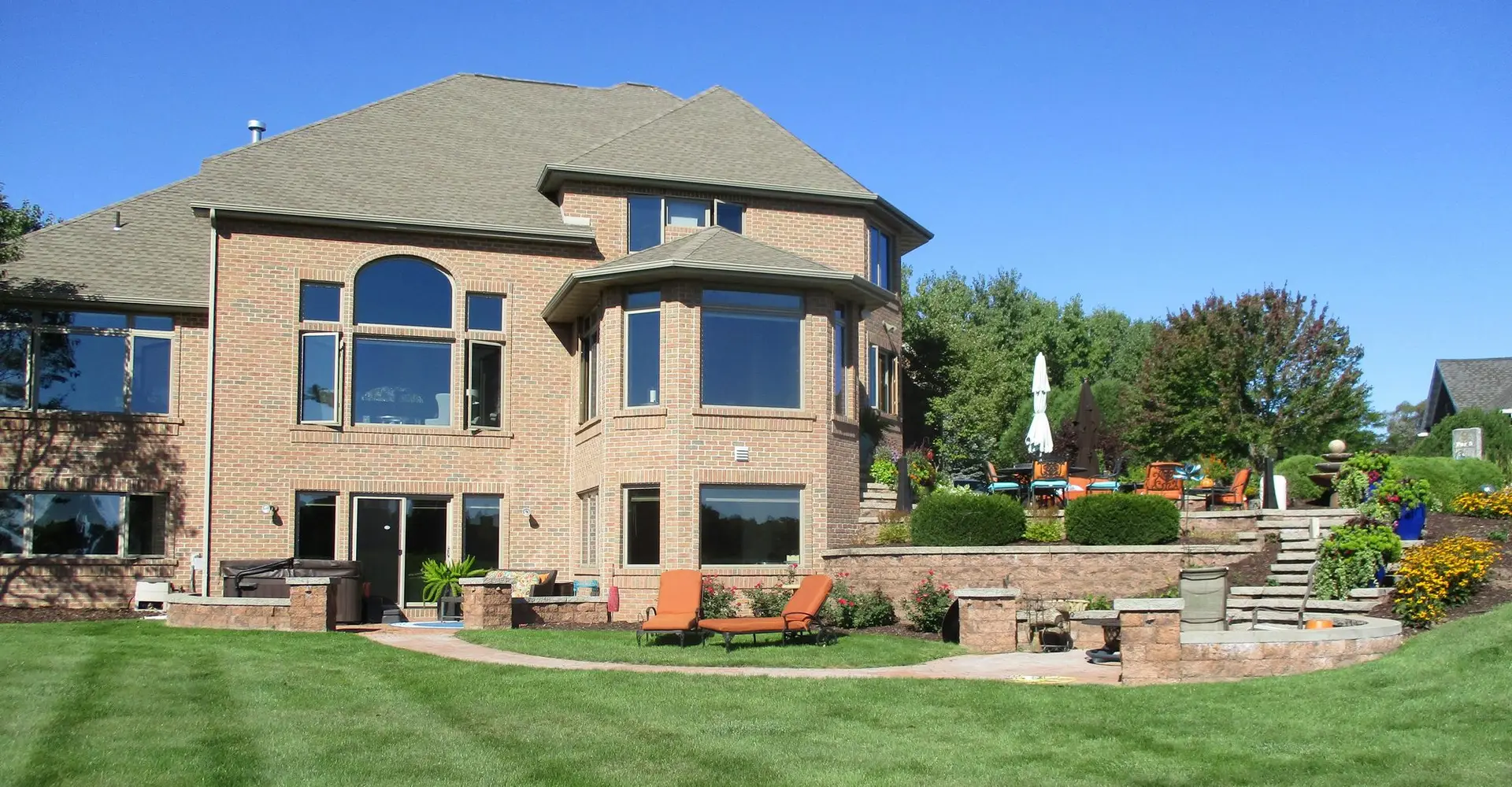 Large brick home with landscaped backyard patio