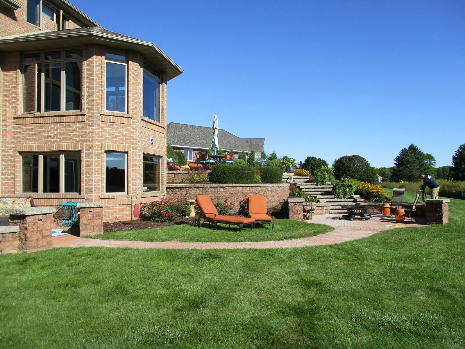 Landscaped backyard patio with lounge chairs and fire pit