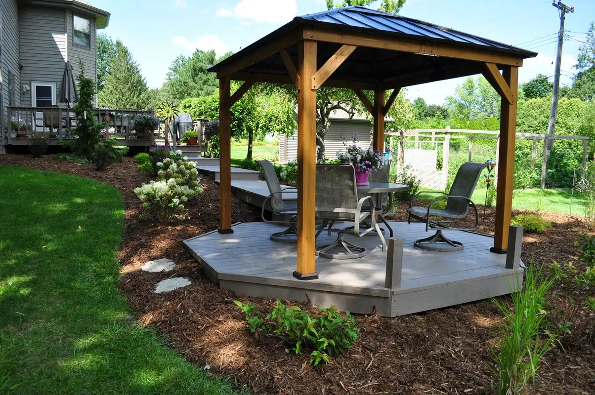 Backyard gazebo with patio furniture and landscaped garden