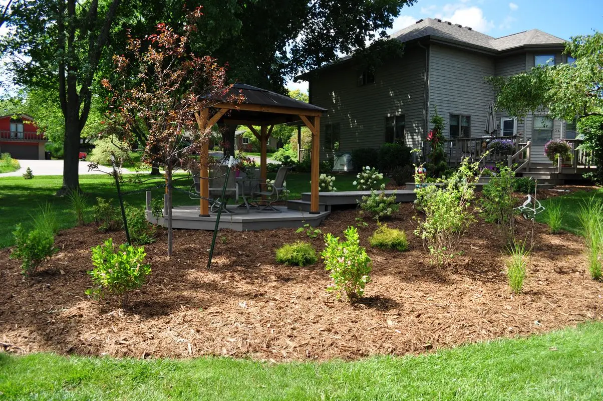 Backyard gazebo surrounded by landscaped garden and shrubs